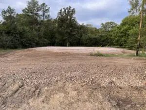 Graded land pad prepared for construction near wooded area