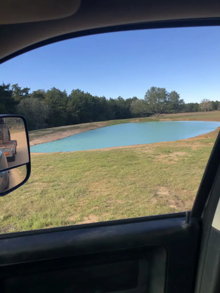 Newly built pond on rural land viewed from inside vehicle
