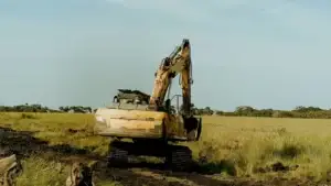 Tracked excavator crossing soft ground on a rural land-clearing site
